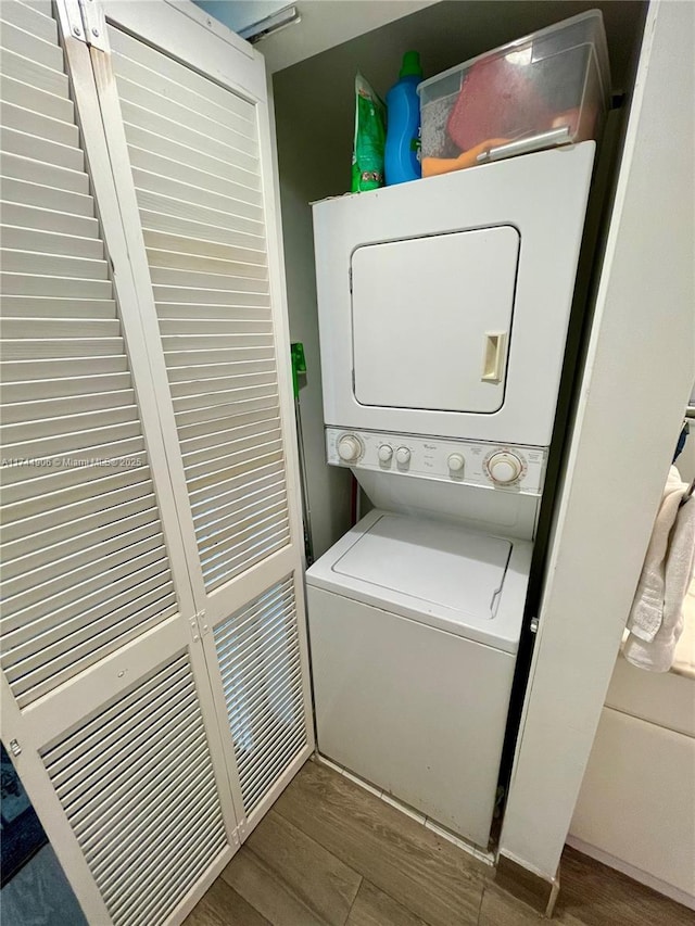 washroom with dark hardwood / wood-style flooring and stacked washing maching and dryer