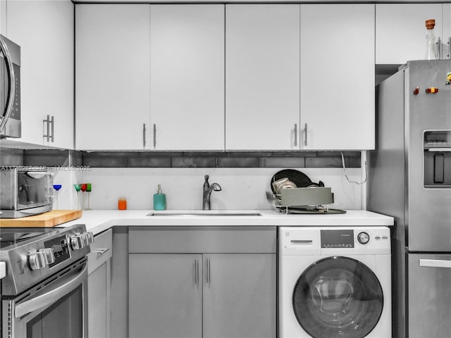 kitchen with white cabinetry, sink, washer / dryer, and stainless steel appliances