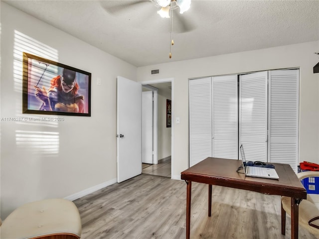 office area with ceiling fan, light hardwood / wood-style flooring, and a textured ceiling