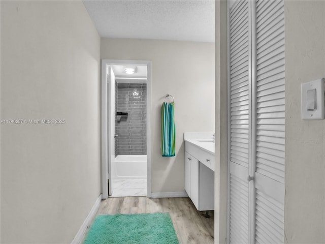 bathroom with vanity, tiled shower / bath combo, a textured ceiling, and hardwood / wood-style flooring