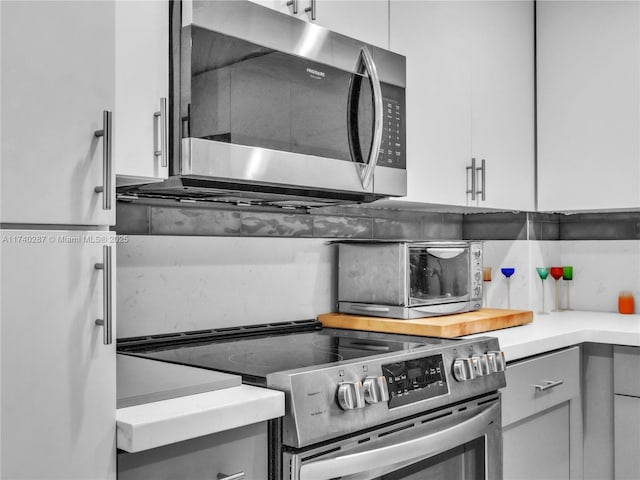 kitchen with backsplash, gray cabinets, and stainless steel appliances