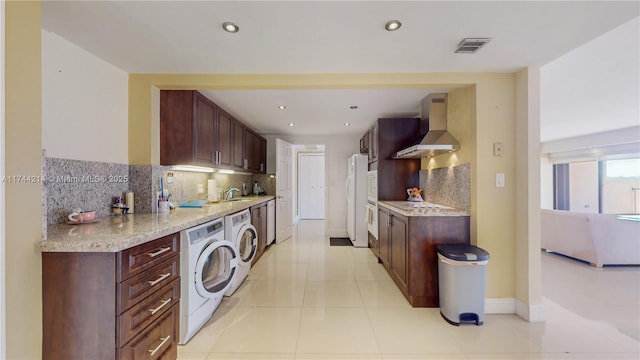 kitchen with tasteful backsplash, white refrigerator, light tile patterned floors, independent washer and dryer, and wall chimney exhaust hood