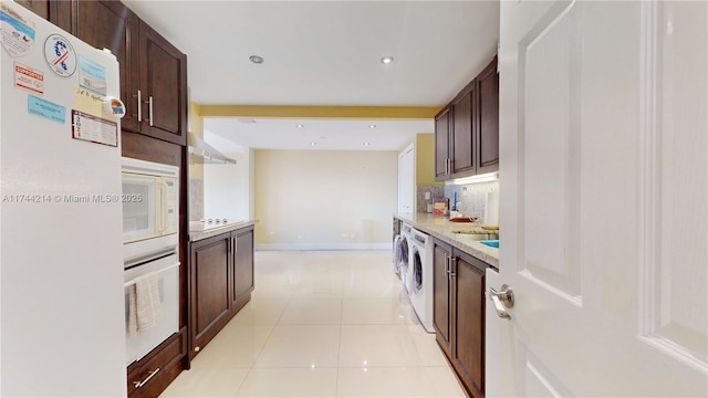 kitchen with light tile patterned flooring, white appliances, dark brown cabinets, and decorative backsplash