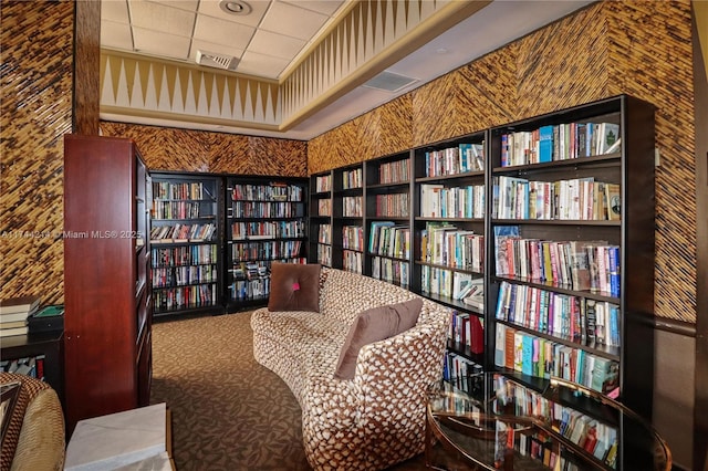 living area featuring carpet flooring and a drop ceiling