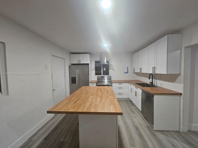 kitchen with white cabinets, appliances with stainless steel finishes, sink, and butcher block countertops