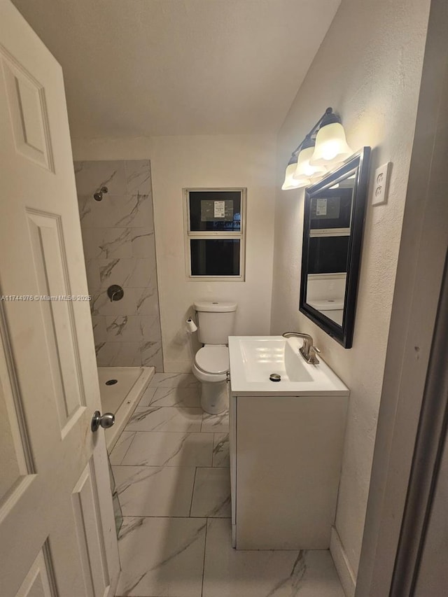 bathroom with vanity, toilet, and tiled shower