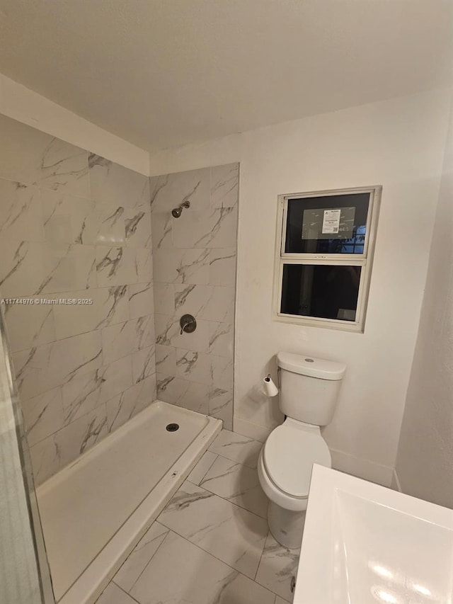 bathroom featuring tiled shower and toilet