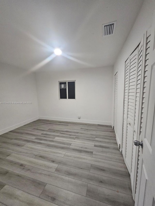 unfurnished bedroom featuring light hardwood / wood-style flooring and multiple closets