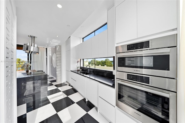 kitchen with white cabinets, stainless steel double oven, plenty of natural light, and sink