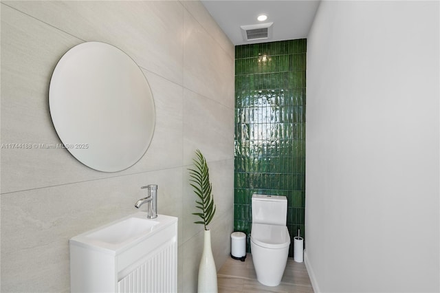 bathroom featuring tile walls, vanity, and toilet