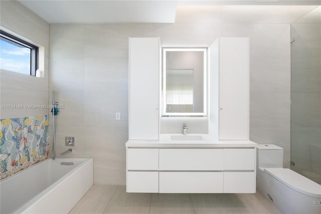 full bathroom featuring toilet, tile walls, tiled shower / bath, and vanity