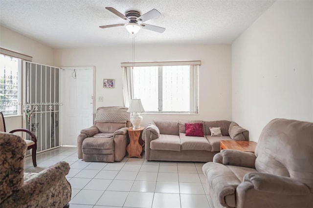 living room with light tile patterned flooring, ceiling fan, and a textured ceiling