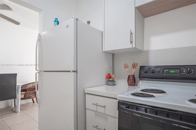 kitchen with white cabinets, light tile patterned floors, white fridge, and range with electric stovetop