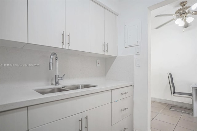 kitchen featuring sink, light tile patterned floors, ceiling fan, tasteful backsplash, and white cabinets