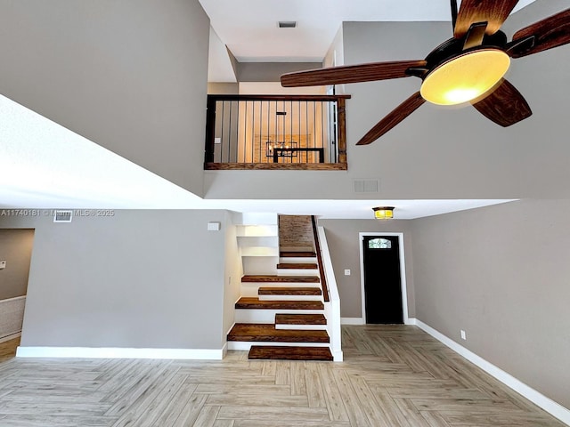 stairway featuring ceiling fan, parquet flooring, and a towering ceiling