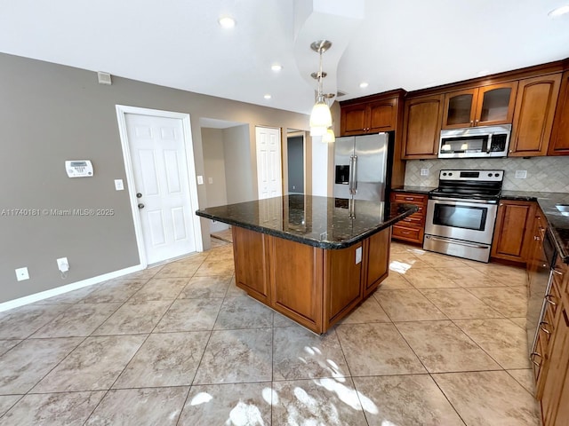 kitchen with dark stone countertops, appliances with stainless steel finishes, a kitchen island, pendant lighting, and decorative backsplash