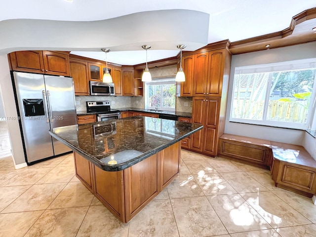 kitchen with decorative light fixtures, backsplash, dark stone counters, a center island, and stainless steel appliances