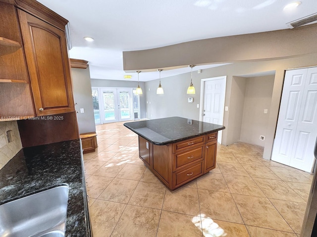 kitchen featuring sink, dark stone countertops, backsplash, a kitchen island, and french doors