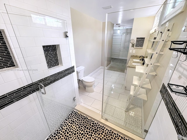 bathroom featuring vanity, toilet, a shower with door, and tile patterned flooring