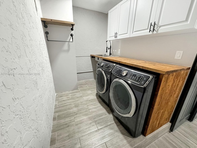 laundry area featuring cabinets, washing machine and clothes dryer, and sink