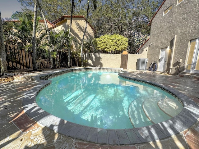 view of swimming pool featuring central AC unit and a patio