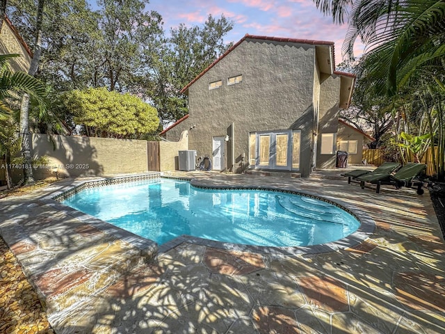 pool at dusk with a patio and central air condition unit