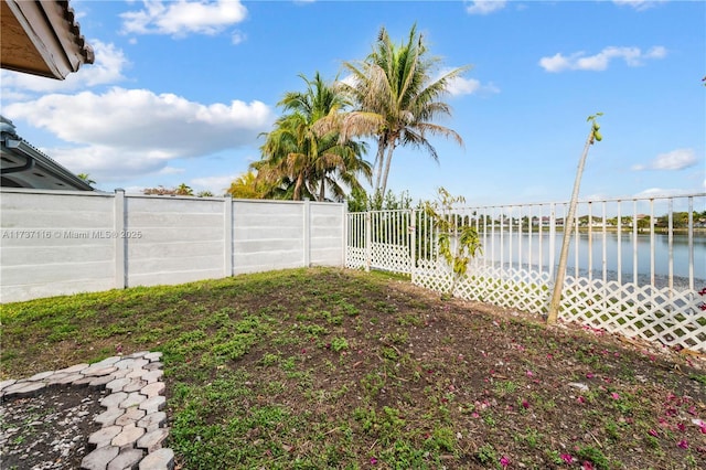 view of yard featuring a water view and a fenced backyard