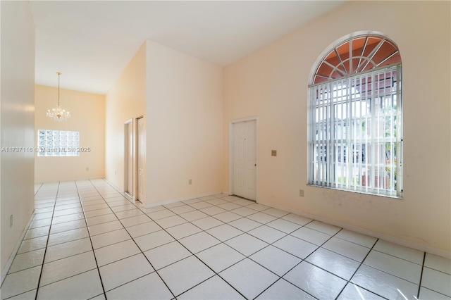 unfurnished room featuring light tile patterned flooring, a towering ceiling, and an inviting chandelier