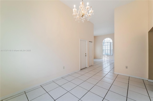 spare room featuring a notable chandelier, baseboards, and light tile patterned floors