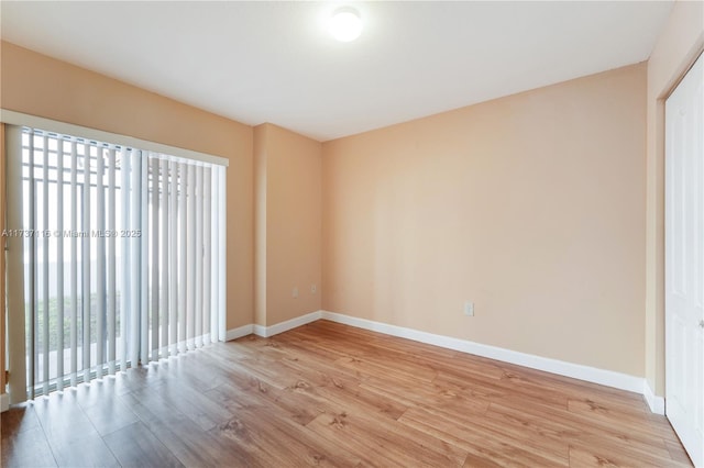 empty room featuring baseboards and light wood finished floors