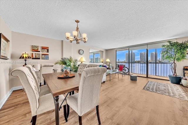 dining area with floor to ceiling windows, a textured ceiling, a chandelier, and light hardwood / wood-style flooring