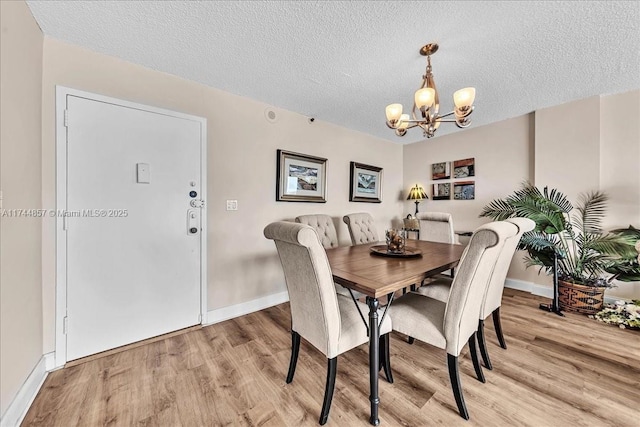 dining area with a chandelier, a textured ceiling, and light hardwood / wood-style floors