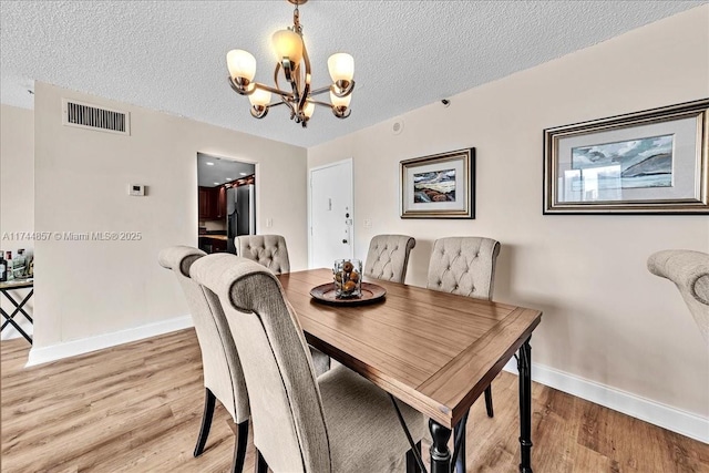 dining space featuring hardwood / wood-style flooring, a textured ceiling, and a chandelier