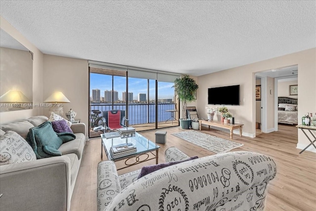 living room featuring floor to ceiling windows, light hardwood / wood-style floors, and a textured ceiling