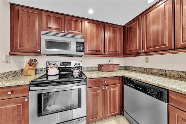 kitchen featuring light stone counters, light tile patterned floors, and stainless steel appliances