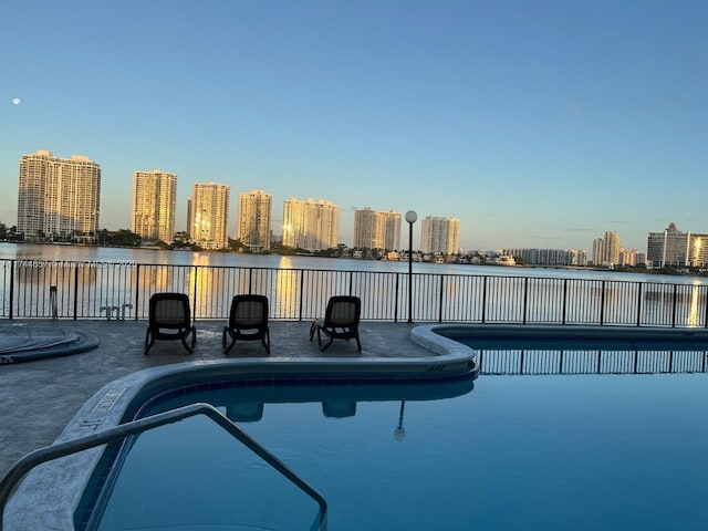 view of swimming pool with a patio area and a water view