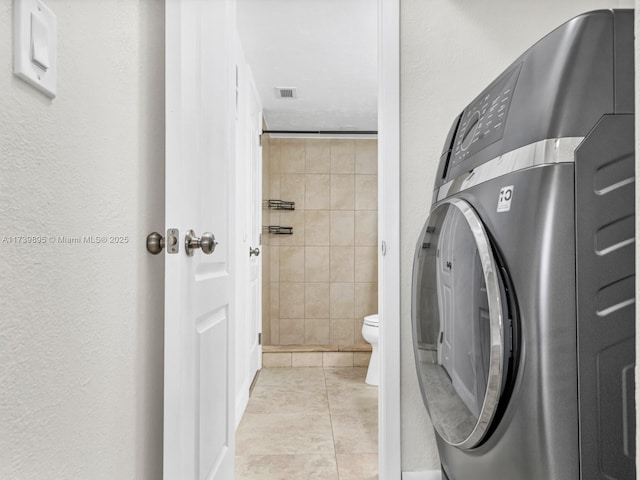 bathroom with tile patterned floors, visible vents, toilet, washer / clothes dryer, and a textured wall