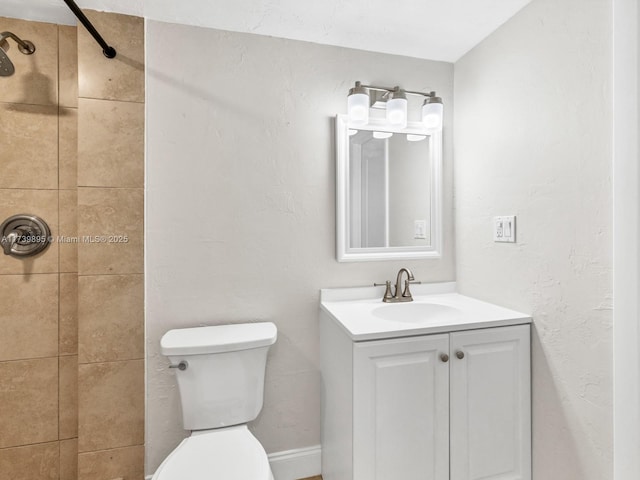 full bath featuring toilet, tiled shower, and vanity