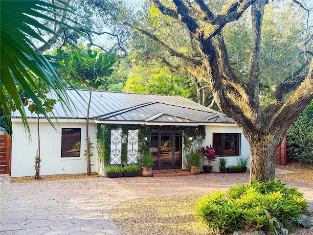 ranch-style house with stucco siding, a standing seam roof, metal roof, and french doors