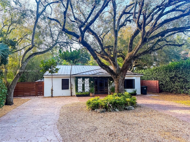 view of front of house featuring metal roof, fence, and stucco siding