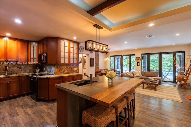 kitchen with range with electric cooktop, a sink, hanging light fixtures, stainless steel microwave, and glass insert cabinets