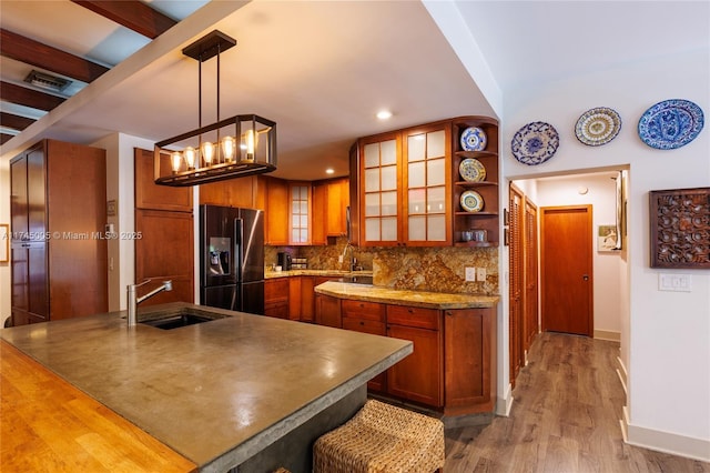 kitchen featuring a sink, black fridge with ice dispenser, open shelves, glass insert cabinets, and pendant lighting