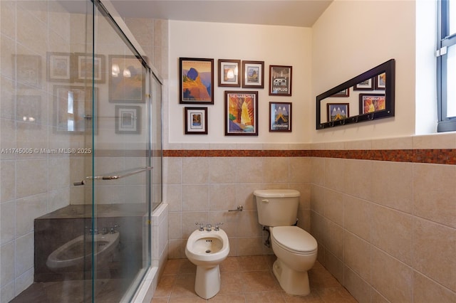 bathroom featuring toilet, tile walls, a shower stall, tile patterned floors, and a bidet