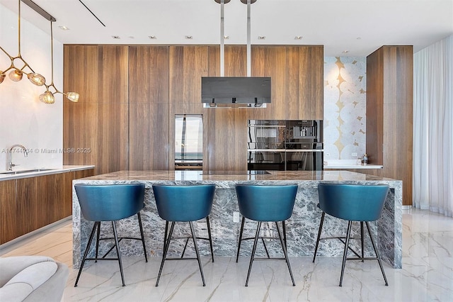 kitchen featuring hanging light fixtures, sink, a center island, and a kitchen bar