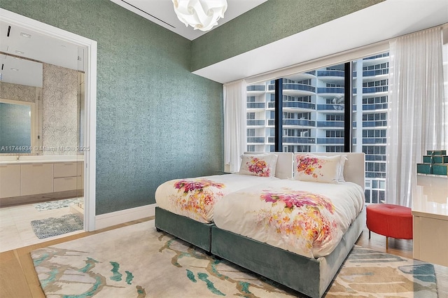 bedroom featuring a notable chandelier, hardwood / wood-style flooring, and ensuite bath