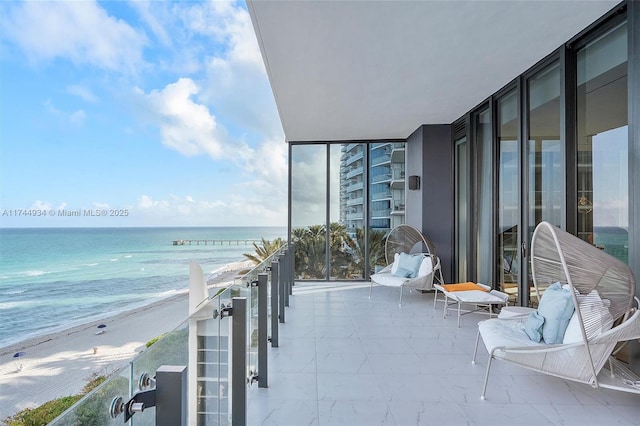 balcony featuring a water view and a view of the beach