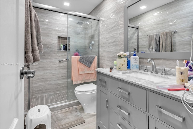 bathroom with tile walls, vanity, and an enclosed shower