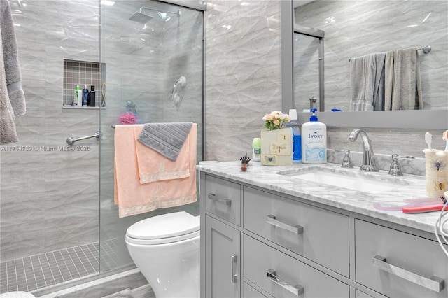 bathroom with tile walls, vanity, an enclosed shower, decorative backsplash, and toilet