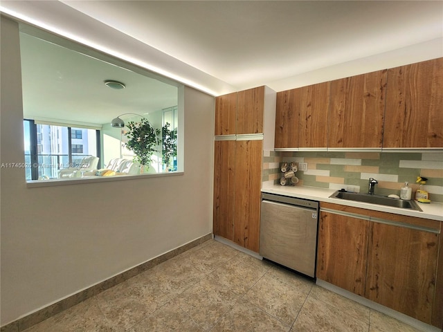 kitchen featuring tasteful backsplash, a sink, light countertops, brown cabinets, and stainless steel dishwasher