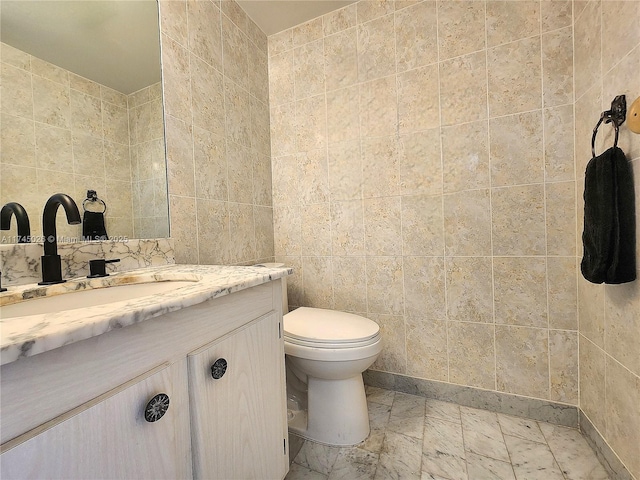 bathroom featuring vanity, tile walls, and toilet